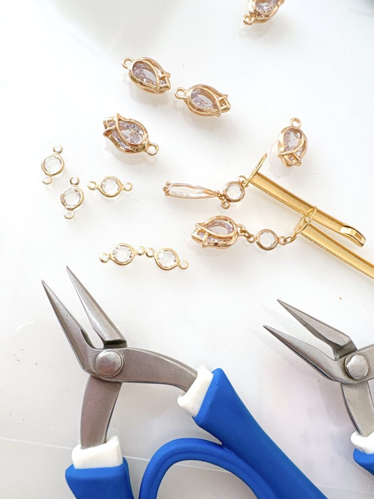 「ゴールドのジュエリーパーツと工具を並べたアクセサリー制作風景。チャームづくりの繊細な作業工程を写した画像。」