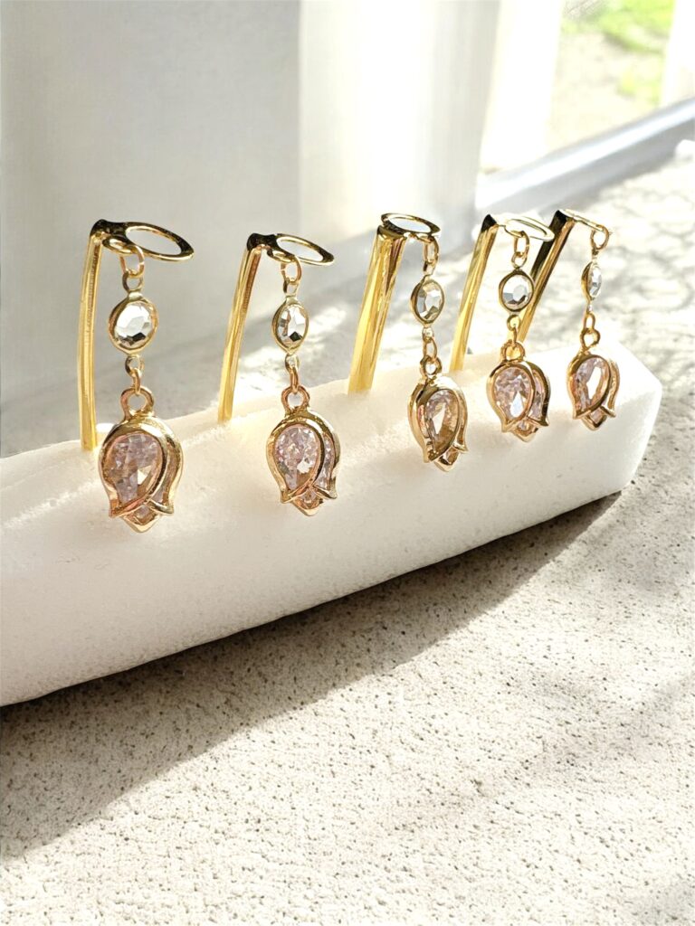 「ゴールドフレームにクリスタルが揺れるエレガントなピアス。光を受けて輝く上品なデザインのチャーム。」