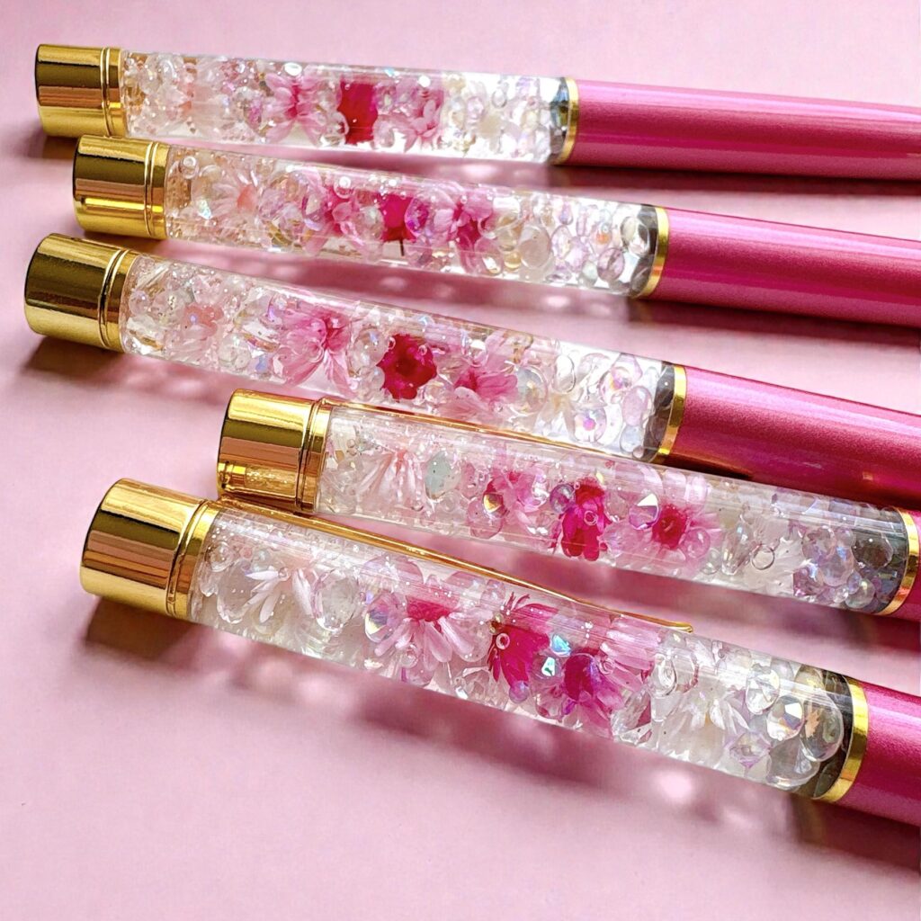 ピンク背景に並べた桜のハーバリウムボールペン
