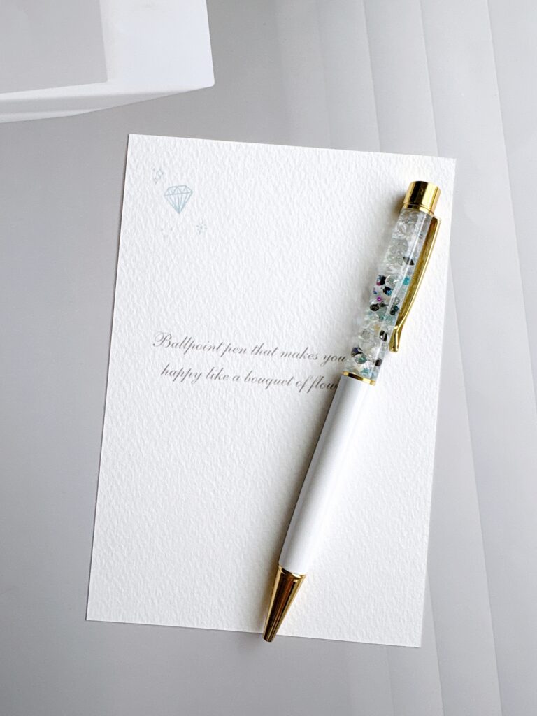 白いカードの上に置かれた透明感のあるオーダーハーバリウムボールペンの写真