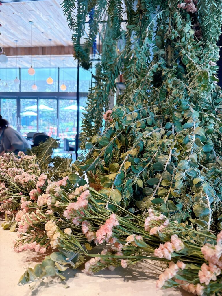 テーブルに広がるグリーンと淡いピンクの花。自然の重なりがやわらかな空気をつくっている。
