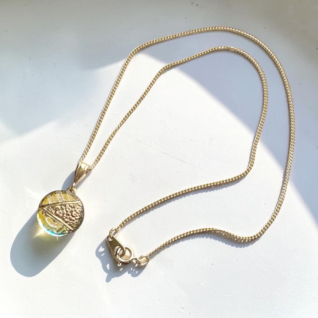 チェコガラスのネックレス「光のしずく -A Quiet Glow-」。シャンパンゴールドとオーロラの輝きを楽しめるペンダント。
