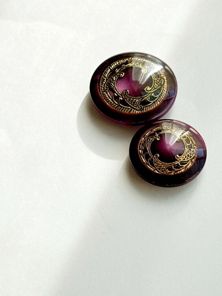 深いパープルに金色の装飾が施されたヴィンテージ調のボタン2点